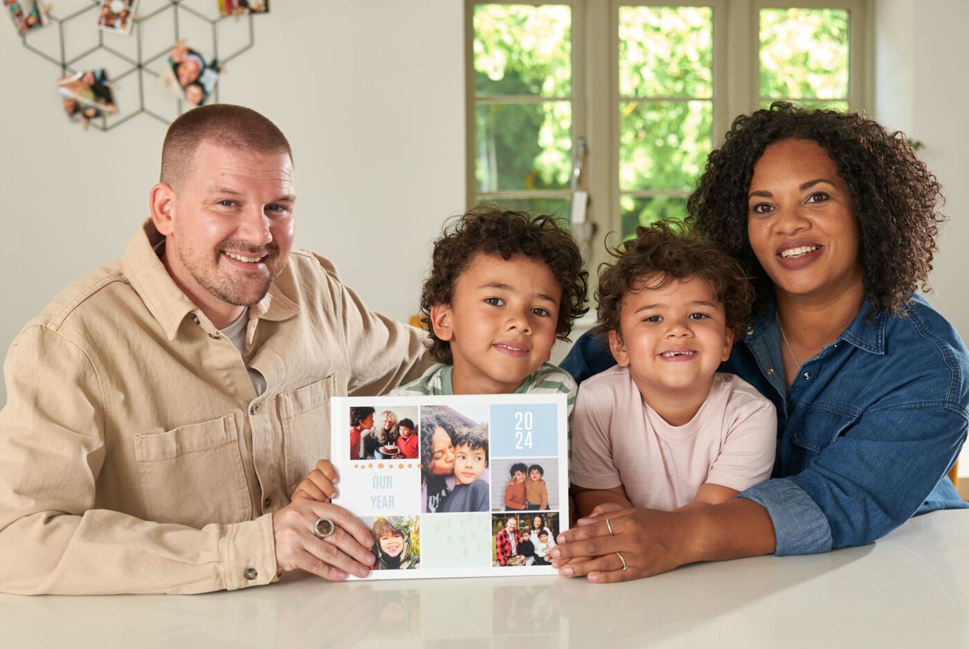 Family cheerfully poses with a CEWE photo book in hand.