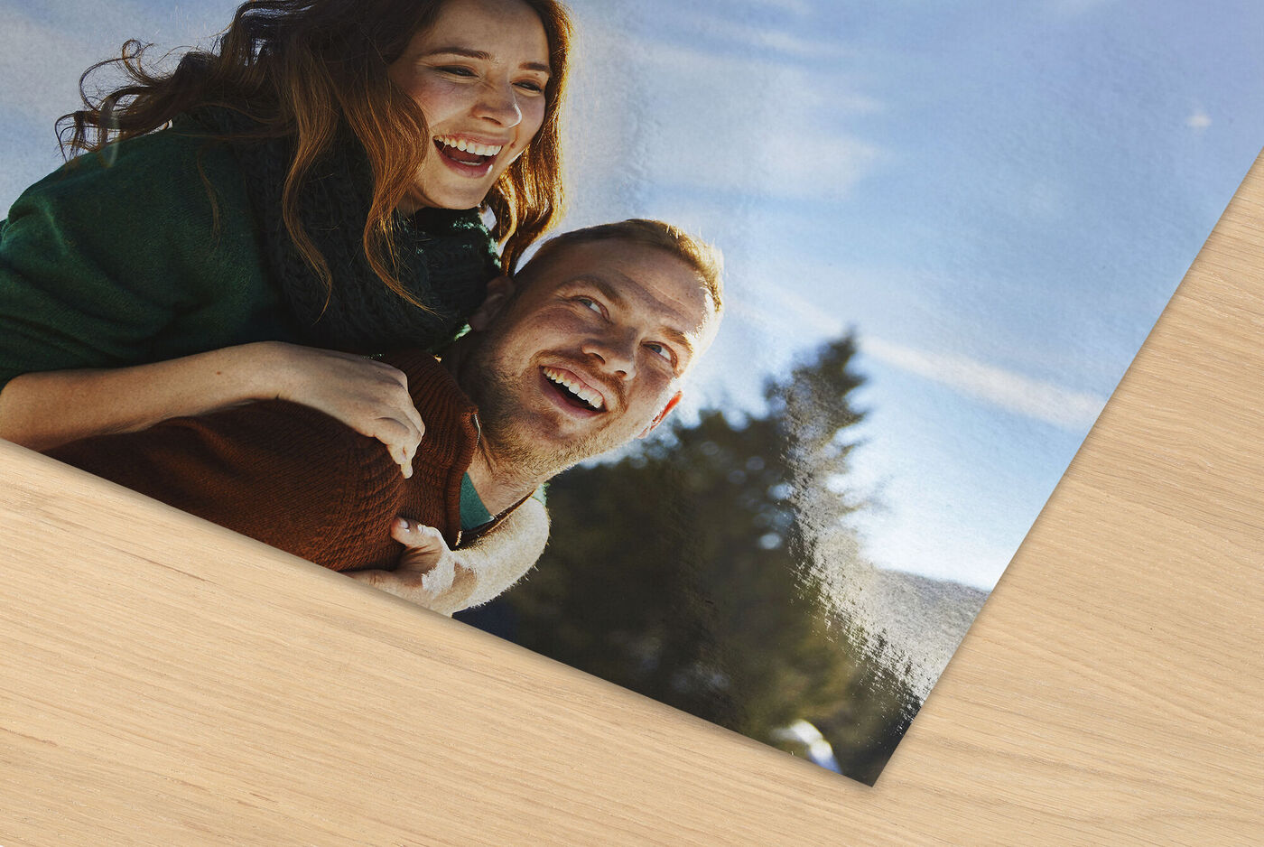 Two people hugging in front of a picturesque landscape with trees and sky.
