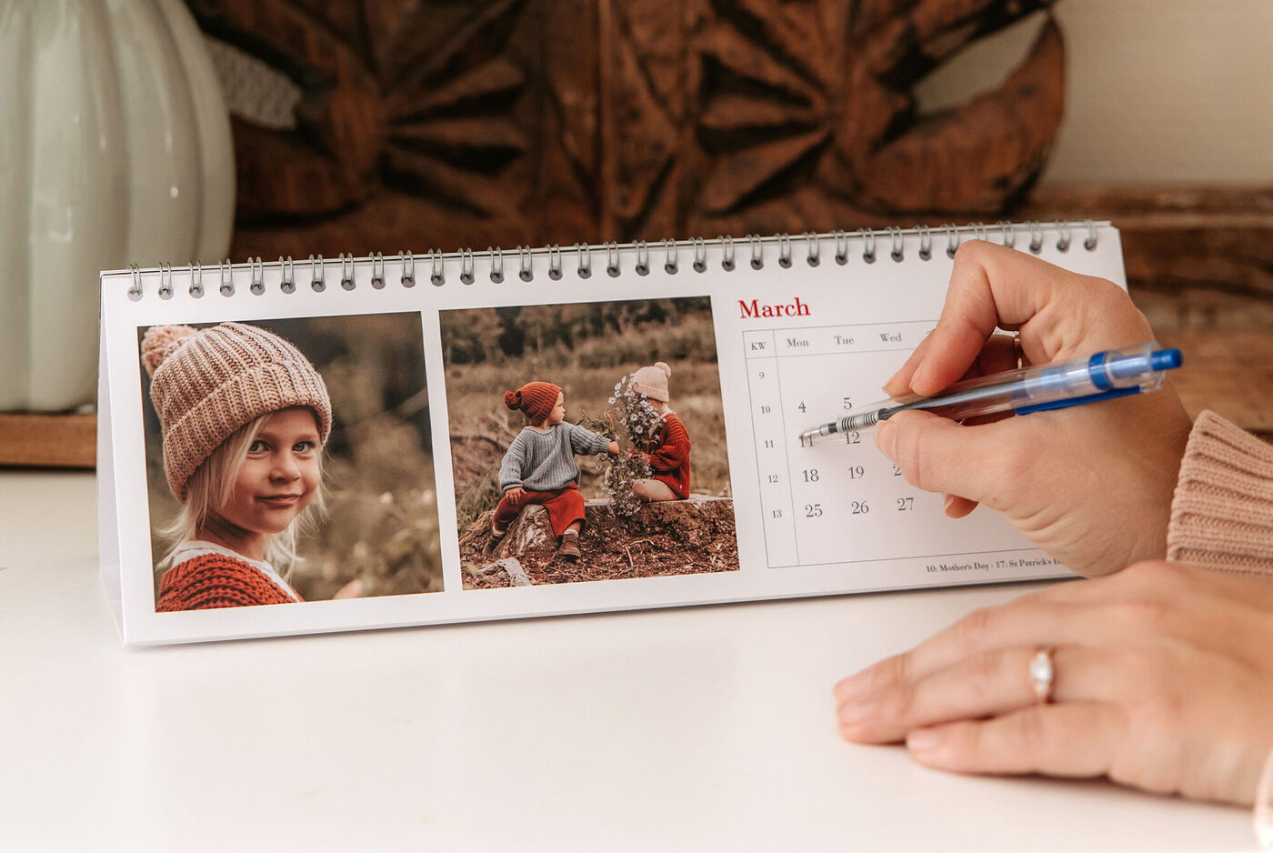 Hand writes in a calendar with two pictures of children outdoors.